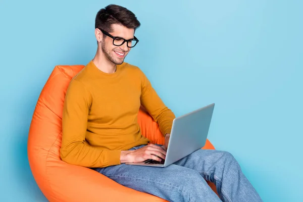 Profil côté photo de jeune homme d'affaires heureux sourire travail ordinateur portable projet de dactylographie chaise assise isolé sur fond de couleur bleue — Photo