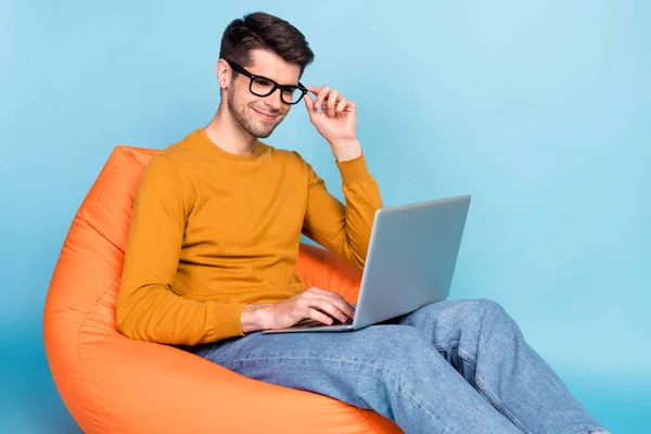 Portrait of attractive focused cheery guy sitting in chair using laptop writing e-mail isolated over bright blue color background — Stock Photo, Image