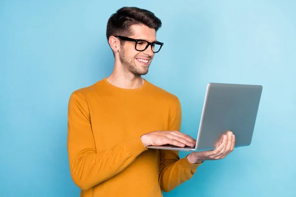 Foto de engraçado morena millennial trabalhador tipo laptop desgaste óculos camisola marrom isolado no fundo de cor azul — Fotografia de Stock