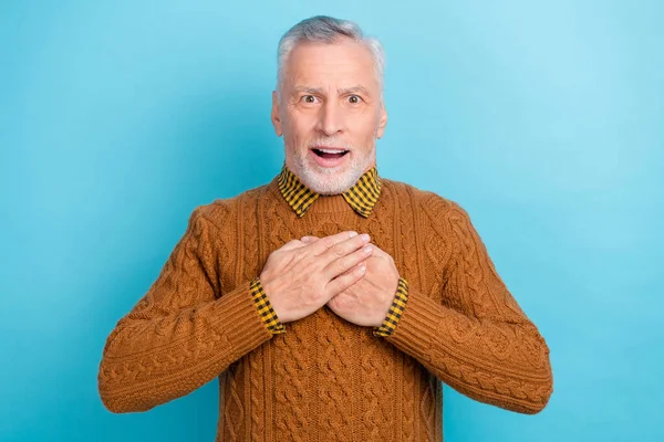 Fénykép elég lenyűgözött nyugdíjas férfi viselni barna pulóver karok mellkas nyitott száj elszigetelt kék színű háttér — Stock Fotó