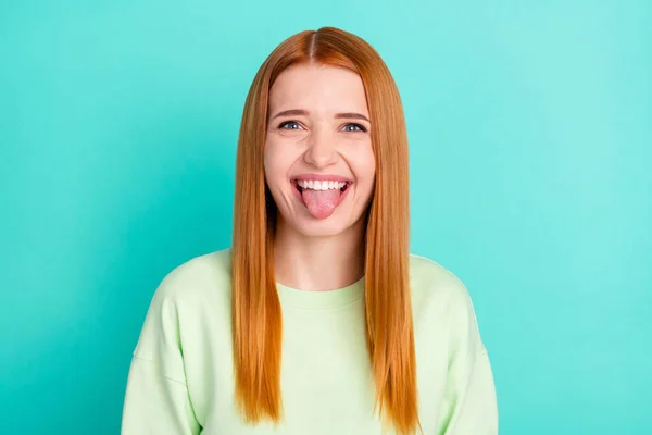 Foto retrato de mostrando língua menina de cabelos vermelhos sorrindo isolado no fundo de cor teal brilhante — Fotografia de Stock