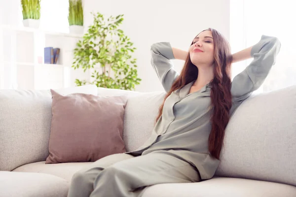 Profilseite Foto von jungen attraktiven Mädchen glücklich positives Lächeln Hände hinter Kopfstütze entspannen Traum Pause sitzen Sofa zu Hause — Stockfoto