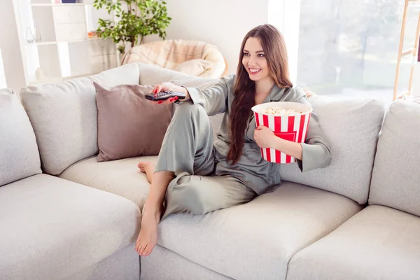 Profilo completo foto laterale di giovane ragazza felice sorriso positivo sedersi divano guardare la televisione tenere popcorn box a casa — Foto Stock