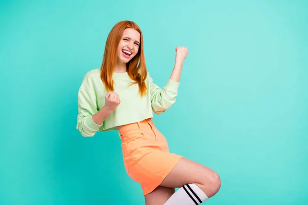 Φωτογραφία από αστείο τυχερός νεαρή γυναίκα φορούν πράσινο στολή αυξάνεται γροθιές χαμογελώντας απομονωμένο τυρκουάζ φόντο χρώμα — Φωτογραφία Αρχείου