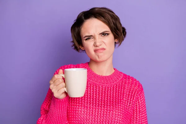 Zdjęcie młodej dziewczyny niezadowolony nieszczęśliwy grymaszenie brzydki zapach trzymać filiżankę herbaty izolowane na fioletowym tle koloru — Zdjęcie stockowe