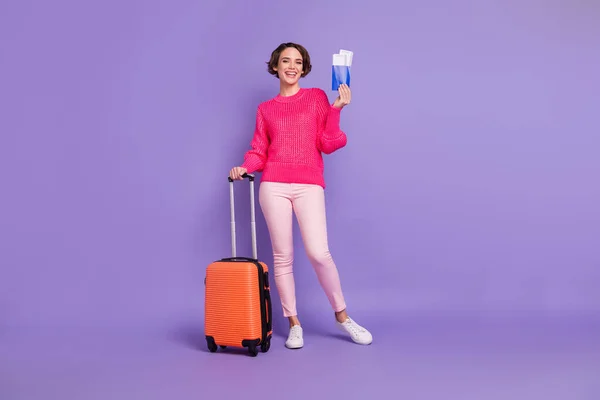 Pełnowymiarowy portret ładnej wesołej pani trzymać walizkę paszport toothy uśmiech odizolowany na fioletowym tle kolor — Zdjęcie stockowe