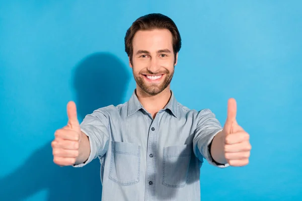 Çekici, neşeli bir adamın portresi, parlak mavi arka planda izole edilmiş iki çift parmak arası reklamı gösteriyor. — Stok fotoğraf