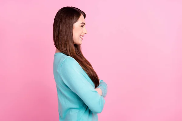 Kuva kiiltävä viehättävä nuori nainen pukeutunut sininen villapaita hymyillen kädet ristissä etsivät tyhjää tilaa eristetty vaaleanpunainen väri tausta — kuvapankkivalokuva