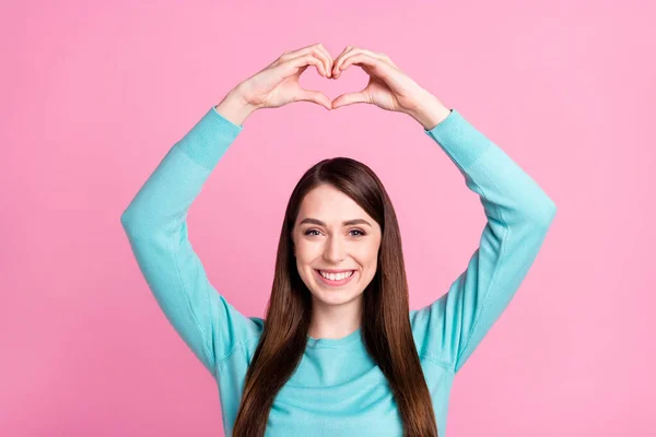 Retrato de menina alegre atraente mostrando sinal de coração sobre a cabeça isolado sobre cor pastel rosa fundo — Fotografia de Stock