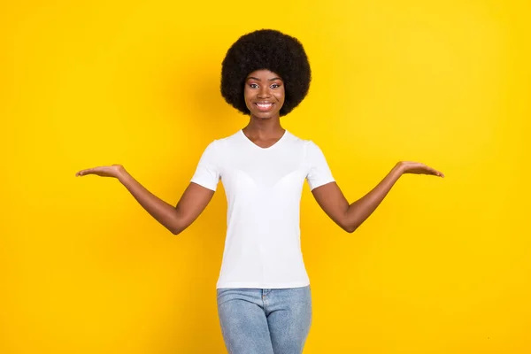 魅力的なアフロアメリカの若い女性の写真手を空のスペースは黄色の色の背景に隔離されたカジュアルな服を着る — ストック写真