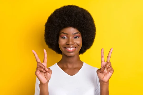 Foto av glada cool mörk hud ung kvinna gör v-tecken leende gott humör isolerad på gul färg bakgrund — Stockfoto