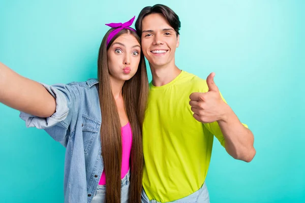 Foto de impressionado morena jovem casal fazer selfie mostrar polegar para cima desgaste amarelo rosa camisetas isoladas no fundo cor teal — Fotografia de Stock