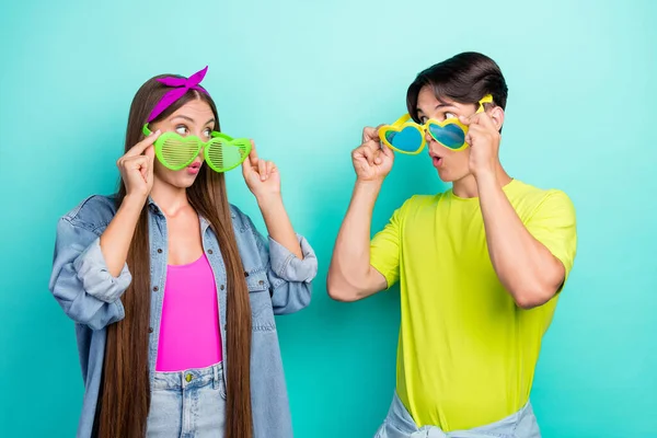 Foto de morena surpreso jovem casal usar óculos rosa amarelo t-shirts hairband isolado no fundo cor turquesa — Fotografia de Stock