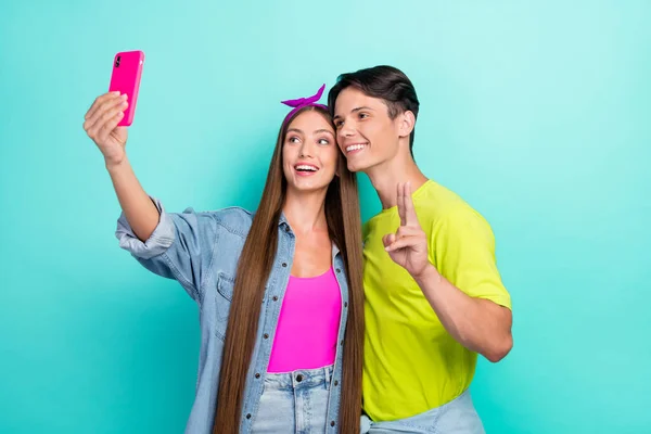 Foto de casal millennial morena funky fazer selfie show v-sign desgaste rosa amarelo t-shirts hairband isolado no fundo cor turquesa — Fotografia de Stock