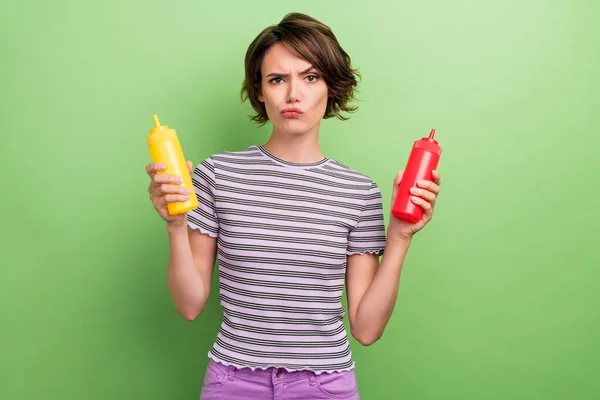 Foto de louca jovem morena senhora imprensa ketchup mostarda desgaste listrado t-shirt isolado no fundo de cor verde — Fotografia de Stock