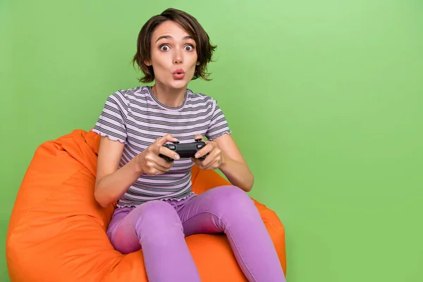 Foto van coole millennial brunette dame playstation zitten op zak dragen t-shirt jeans geïsoleerd op groene achtergrond — Stockfoto