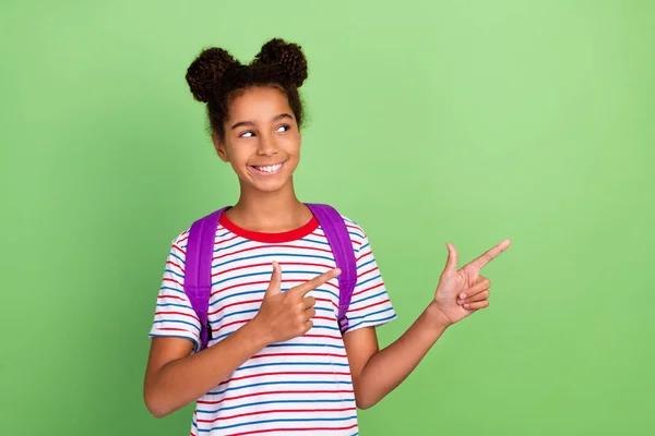 Foto de joven negro escuela chica adolescente mirada indicar dedos vacío espacio promo anuncio aislado sobre verde color de fondo —  Fotos de Stock