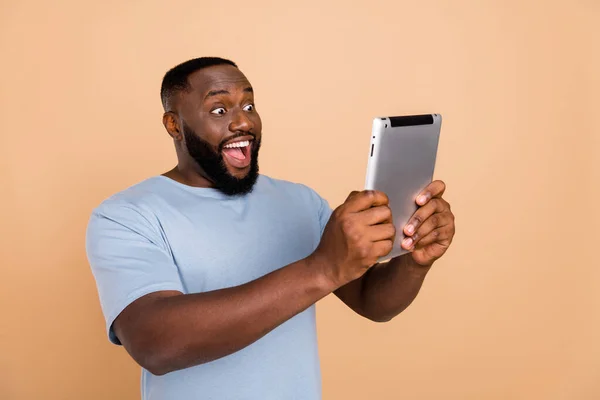 Retrato de chico sorprendido alegre atractivo usando dispositivo gadget mensaje de lectura aislado sobre fondo de color pastel beige —  Fotos de Stock
