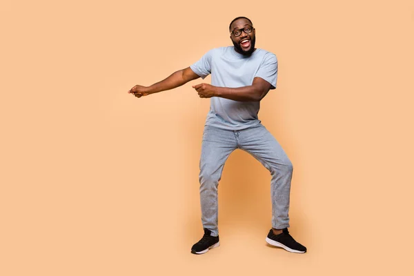 Full längd kroppsstorlek bild av attraktiv glad komisk kille som rör sig med kul isolerad över beige pastell färg bakgrund — Stockfoto