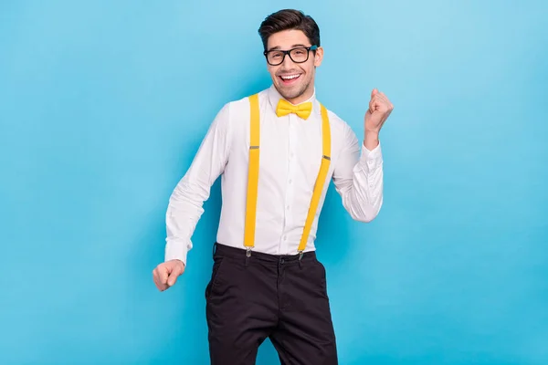 Foto de chico bastante brillante usar tirantes amarillos camisa blanca gafas bailando aislado color azul fondo — Foto de Stock