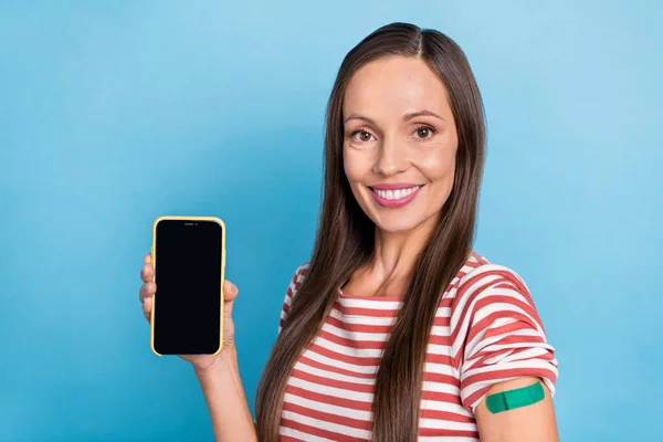 Foto del lado del perfil de una mujer joven demuestra anuncios de pantalla móvil pandemia en línea aislada sobre fondo de color azul — Foto de Stock
