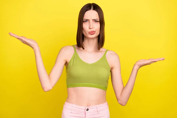 Foto van een hekel brunette millennial dame houden lege ruimte dragen groene singlet jeans geïsoleerd op gele kleur achtergrond — Stockfoto