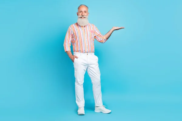 Full size foto di uomo invecchiato felice sorriso positivo tenere mano prodotto promo pubblicizzare isolato su sfondo di colore blu — Foto Stock