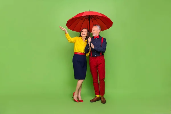 Photo pleine longueur de deux personnes âgées élégantes insouciantes marchent temps pluvieux isolé sur fond de couleur verte — Photo