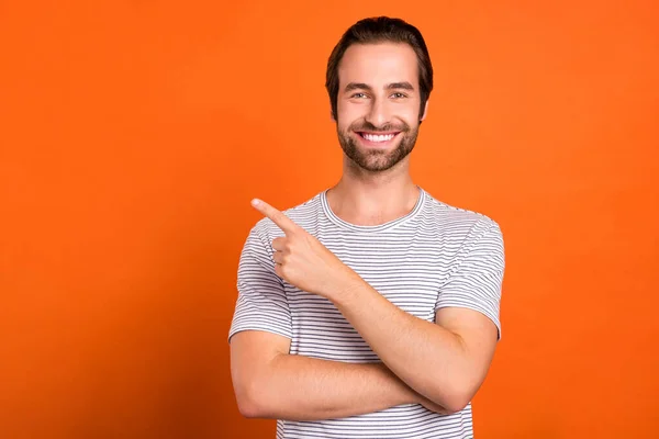 Фото молодого парня указывает пальцем пустое пространство реклама скидка на оранжевый цвет фона — стоковое фото
