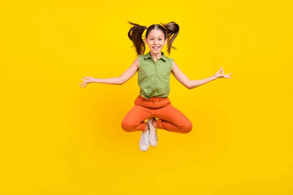 Foto de menina estudante doce funky usar camisa verde sorrindo pulando alto praticando ioga isolado cor amarela fundo — Fotografia de Stock