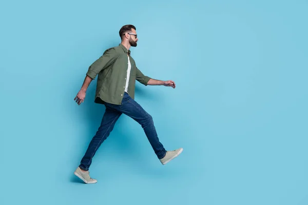 Foto de perfil de tipo turista confiado caminar usar anteojos camisa verde jeans calzado aislado color azul fondo — Foto de Stock