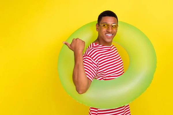 Foto van man hipster toeristische punt duim lege ruimte advertenties ring dragen rood gestreepte t-shirt geïsoleerd over glans gele kleur achtergrond — Stockfoto