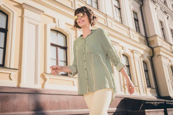 Photo of charming lovely positive lady błyszczący uśmiech spacer nosić sunglass paski spodnie miejskie miasto na zewnątrz — Zdjęcie stockowe