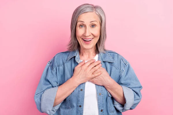 Foto av tacksam gammal kvinna glad humör hålla händerna bröst hjärta isolerad på pastell rosa färg bakgrund — Stockfoto
