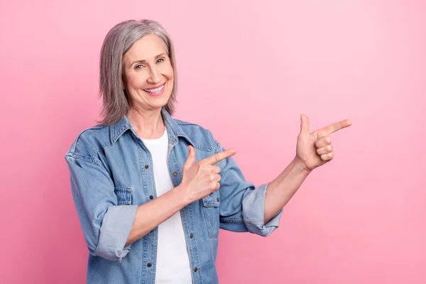 Φωτογραφία από ενθουσιασμένοι ηλικιωμένη κυρία σημείο κενό χώρο φορούν μπλε σακάκι απομονώνονται σε παστέλ ροζ φόντο χρώμα — Φωτογραφία Αρχείου