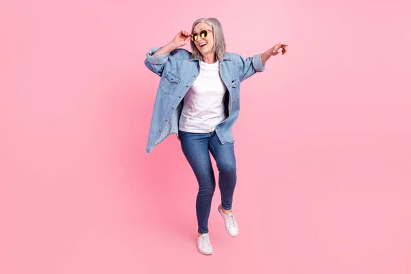 Foto di attraente positivo vecchia donna indossare occhiali da sole musica amante danza isolato su sfondo di colore rosa — Foto Stock