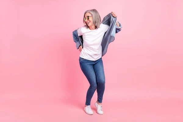 Full body photo of fashionable aged lady look empty space wear shirt jeans isolated on pink background — Stock Photo, Image