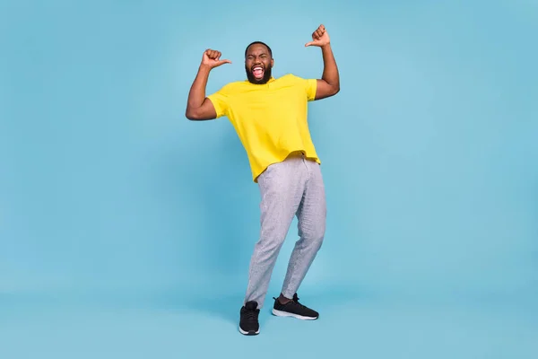 Foto van zoete opgewonden donkere huid guy gekleed geel t-shirt glimlachen wijzende vingers zelf geïsoleerde blauwe kleur achtergrond — Stockfoto