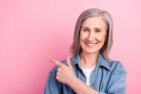 Foto van grappige senior dame punt lege ruimte dragen blauwe jas geïsoleerd op pastel roze kleur achtergrond — Stockfoto