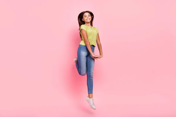 Foto av flirtig sportig aktiv liten dam hoppa håll händerna bära grön topp jeans sneakers isolerad rosa färg bakgrund — Stockfoto