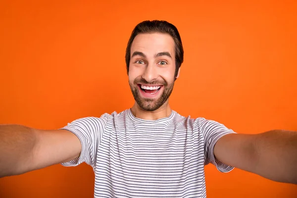 Фотографія молодого веселого чоловіка, який записує відеозапис інфлюенсера селфі ізольовано на помаранчевому кольоровому фоні — стокове фото
