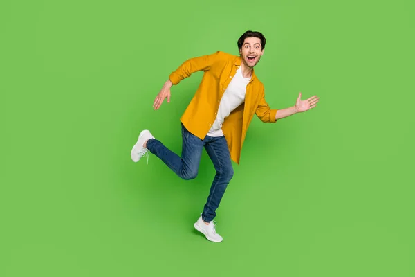 Full-Size-Profil-Seite Foto von jungen lachenden fröhlichen Mann läuft schnelle Geschwindigkeit Reise isoliert auf grünem Hintergrund — Stockfoto