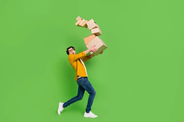 Pełnowymiarowe zdjęcie młodego zszokowanego faceta trzymać pudełka kartonowe spadające przenoszenie izolowane na zielonym tle — Zdjęcie stockowe