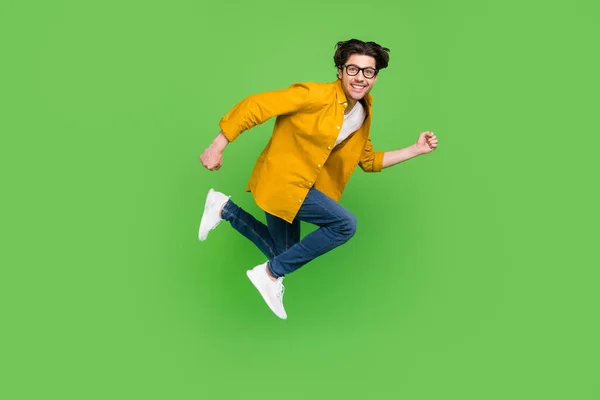 Pleine taille profil côté photo de jeune funky souriant gars dans des lunettes de course dans l'air pressé isolé sur fond de couleur verte — Photo