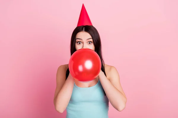 Foto von beeindruckt Millennial Geburtstag Dame blasen Ballon tragen Hut blauen Top isoliert auf rosa Hintergrund — Stockfoto