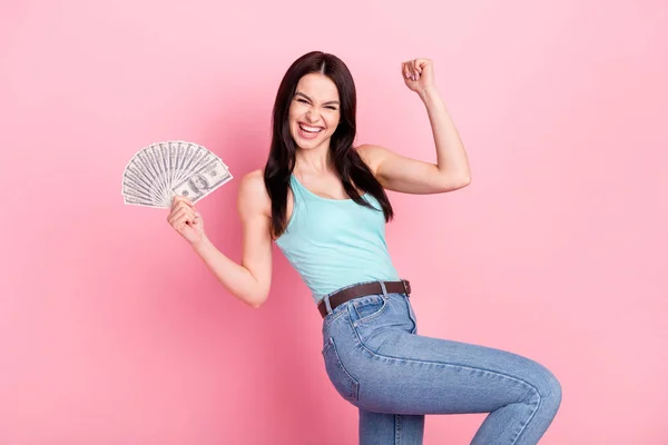 Photo of lucky millennial lady hold money hand fist wear blue top jeans isolated on pink background — Stock Photo, Image