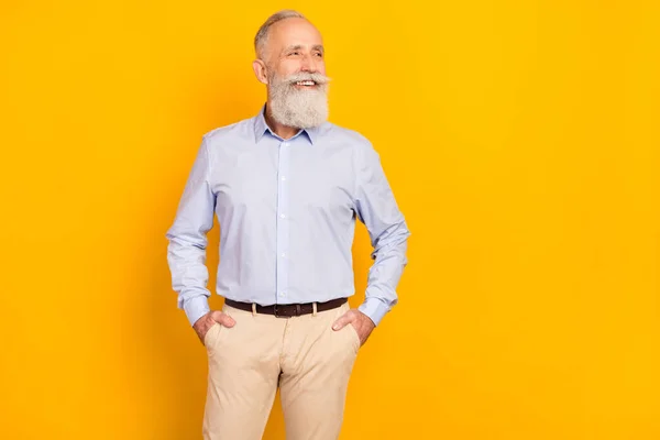 Foto de homem muito maduro doce vestido roupa formal sorrindo bolsos braços olhando espaço vazio isolado cor amarela fundo — Fotografia de Stock