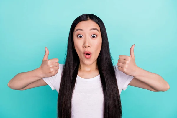 Фотографія молодої привабливої азіатської дівчини вражена шокованою щасливою посмішкою, показують великі пальці, як ізольовані на бірюзовому кольоровому фоні — стокове фото