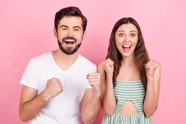 Foto de casal surpreso comemorar vitória levantar punhos usar roupa casual isolado cor-de-rosa fundo — Fotografia de Stock