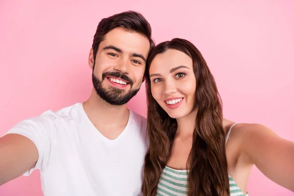Foto de otimista jovem casal cabelo castanho fazer selfie vestir vestido de t-shirt branco isolado na cor rosa backgound — Fotografia de Stock